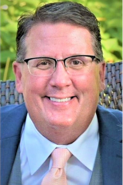 A man in a suit and tie is smiling.