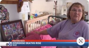 A woman standing in front of a bed with the words overdose death rise.