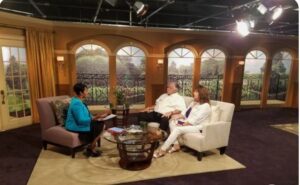 Two people sitting in chairs in a television studio.