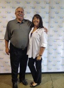 A man and woman posing for a photo in front of a banner.