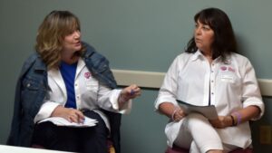 Two women in white coats talking to each other.