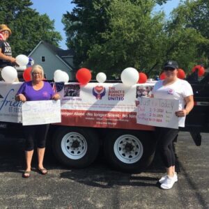 Two ladies holding banners in hand along with a truck