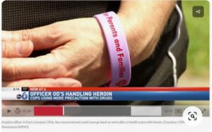 A man is holding a bracelet with a police officer's name on it.